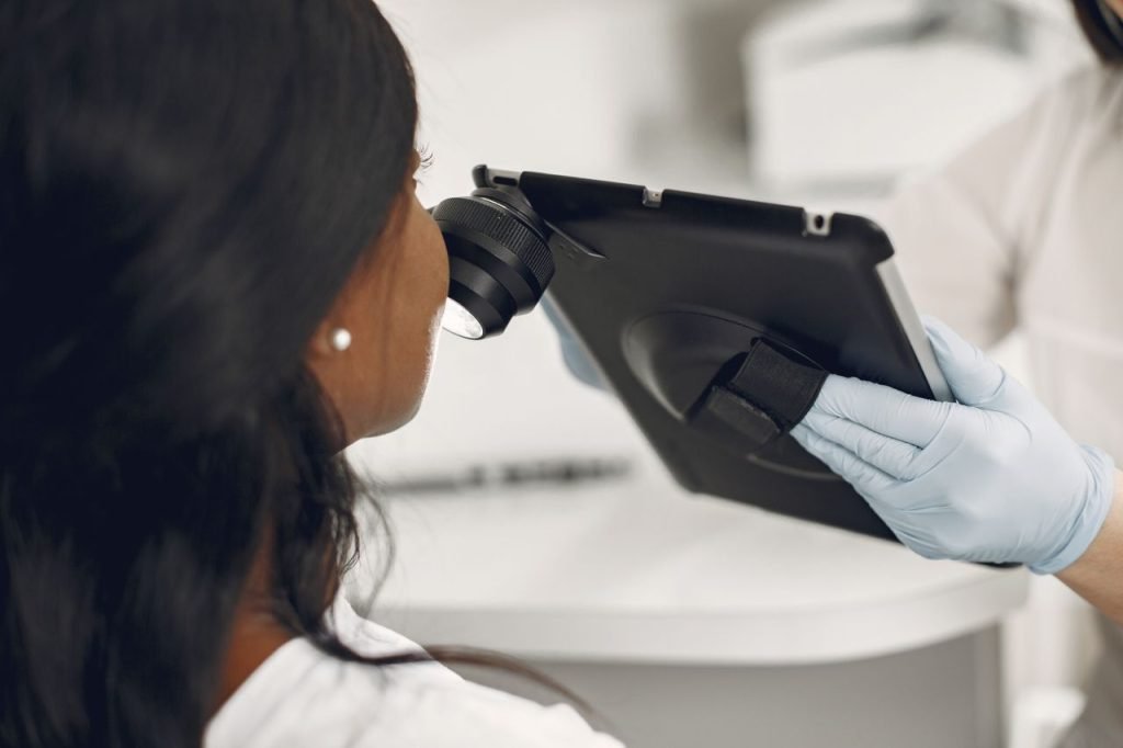 Dermatologist examining a patients skin using a digital dermatoscope and tablet for precision observation.